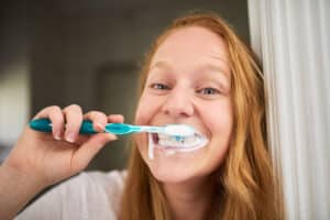 Photo of a young woman brushing her teeth a little too hard