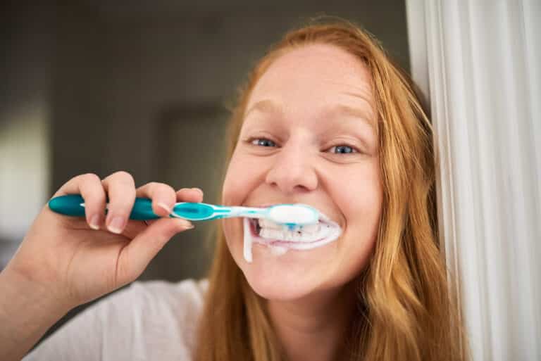 Photo of a young woman brushing her teeth a little too hard