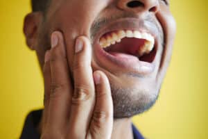 Photo of a young man who has sensitive teeth and wondering why does my tooth hurt when i bite down