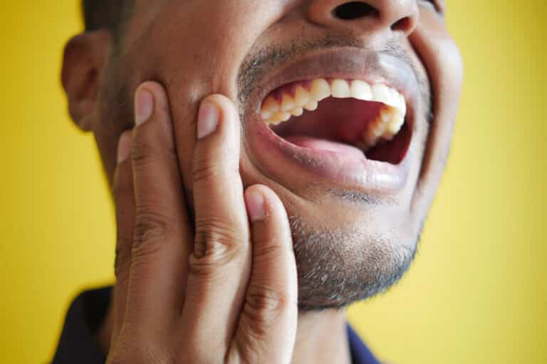 Photo of a young man who has sensitive teeth and wondering why does my tooth hurt when i bite down